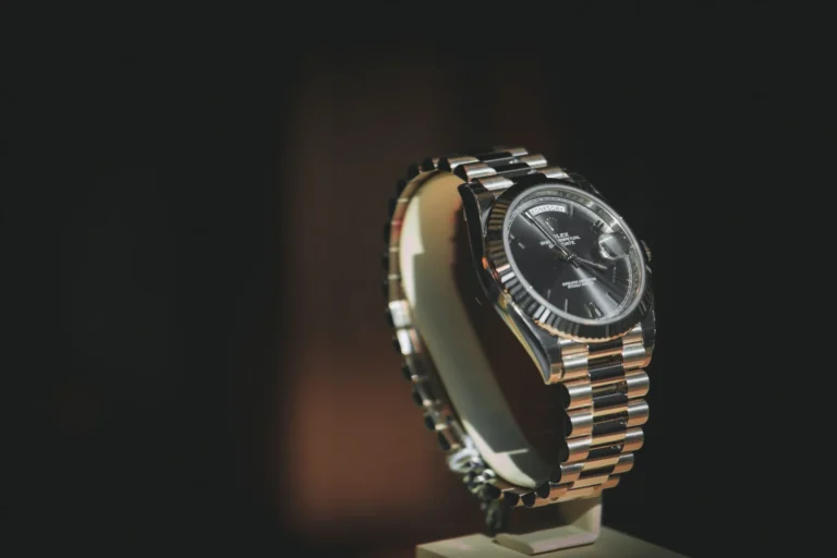 Rolex Day Date Oyster Perpetual watch with a black dial displayed on a stand against a dark background, illustrating how to spot a fake Rolex.
