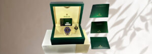 Rolex 'Cookie Monster' Submariner watch displayed in its original green box with warranty card and booklets, showcasing the blue and black bezel design.
