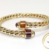 Flexible 14k yellow gold bangle with red tourmaline and yellow citrine gemstones.
