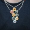 Sterling silver Navajo necklace with semi-precious stone discs and red accents on a black shirt.