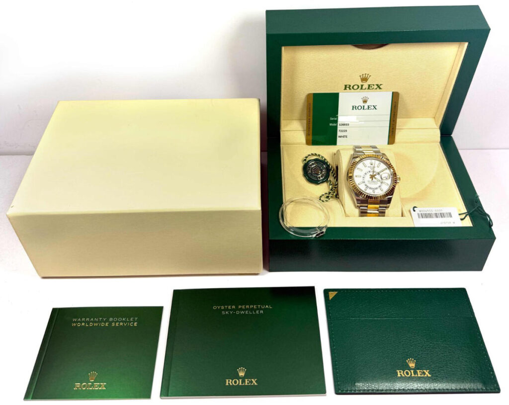 Used Rolex Sky-Dweller watch in original green box with warranty card, booklets, and tags, displayed with its outer packaging and authenticity documents.