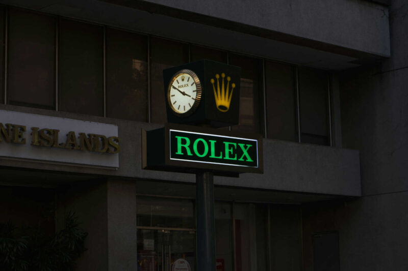 Street sign featuring the Rolex logo and clock, often seen in discussions about Rolex nicknames.