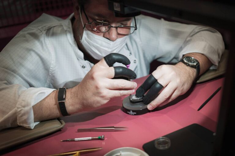 watchmaker performing luxury watch servicing and maintenance with precision tools at a workbench