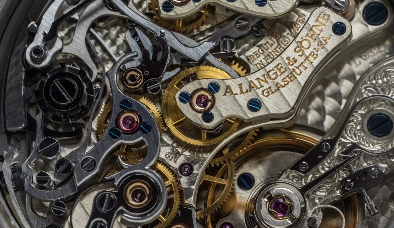 Luxury watch movement with visible gears, screws, and engraved A. Lange and Söhne details